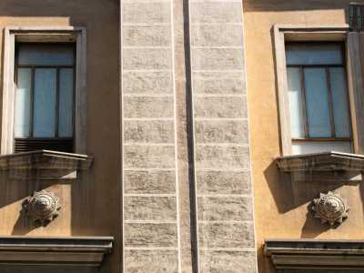 Tale separazione si sviluppa anche in verticale e in modo alternato tra le finestre, attraverso paraste binate in pietra bianca inglobate nel prospetto